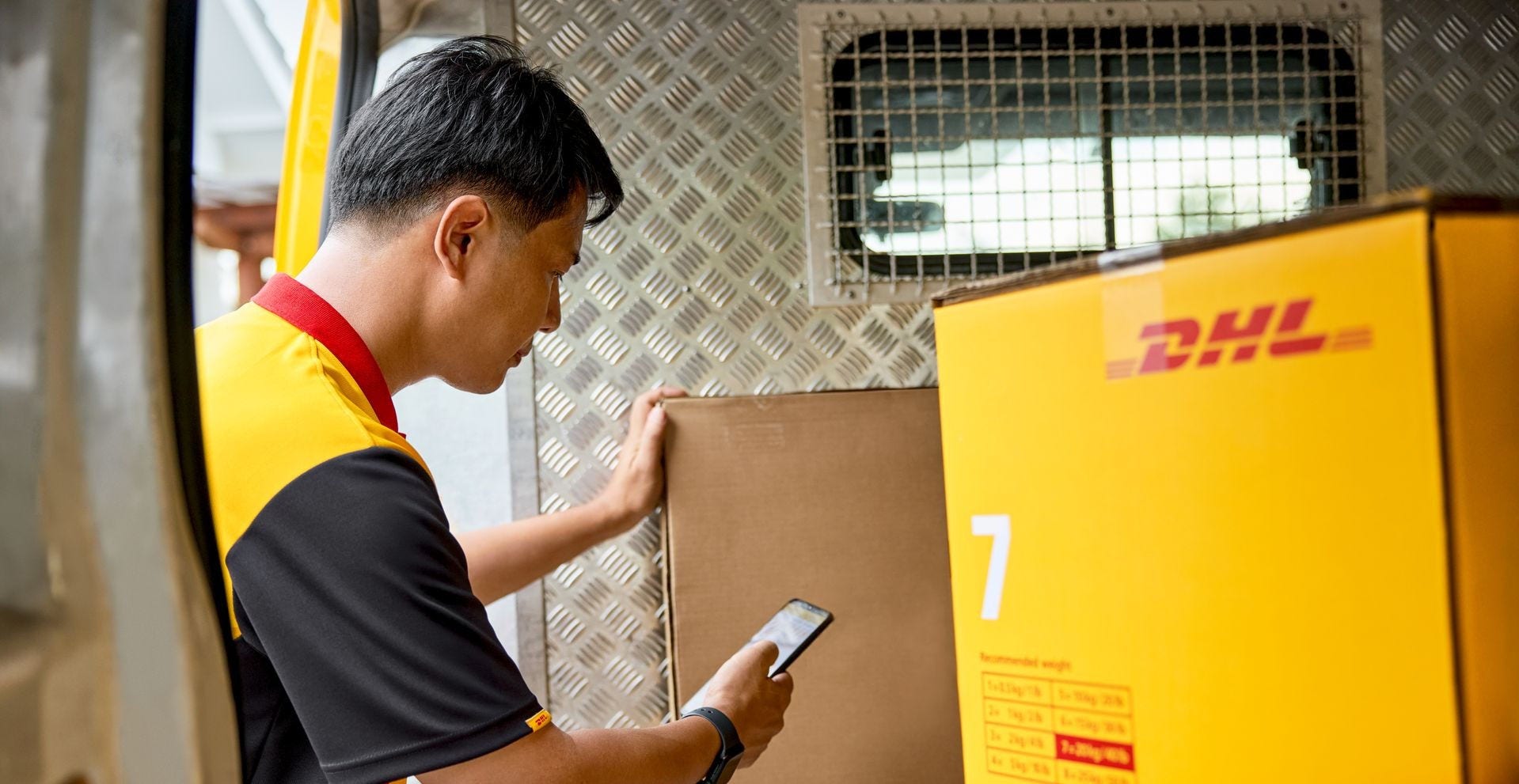 A DHL Express employee scans a DHL heavy parcel in his van.