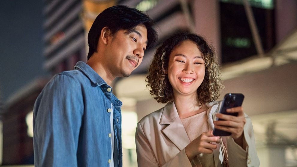 female and male customer with a dhl express envelope under his arm walking in a city at night