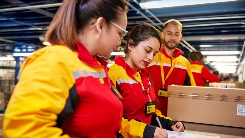 dhl express employees checking documentation for shipping automotive parts