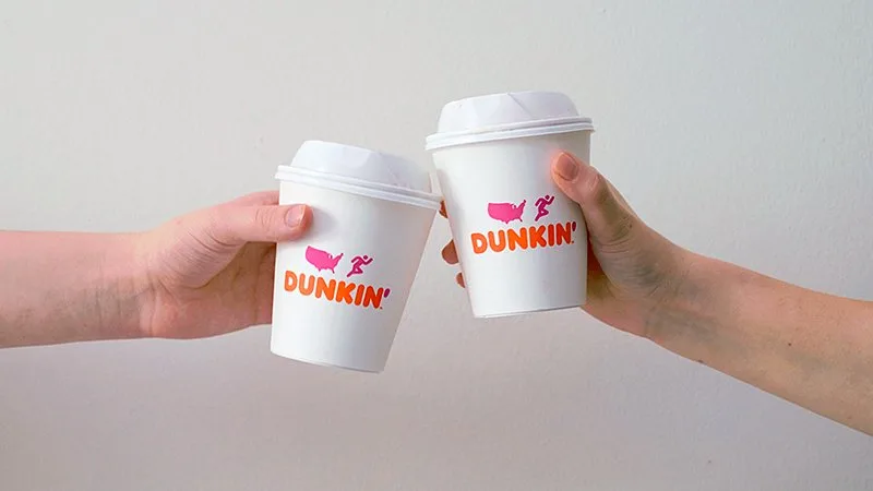 two hands holding dunkin' donuts cups
