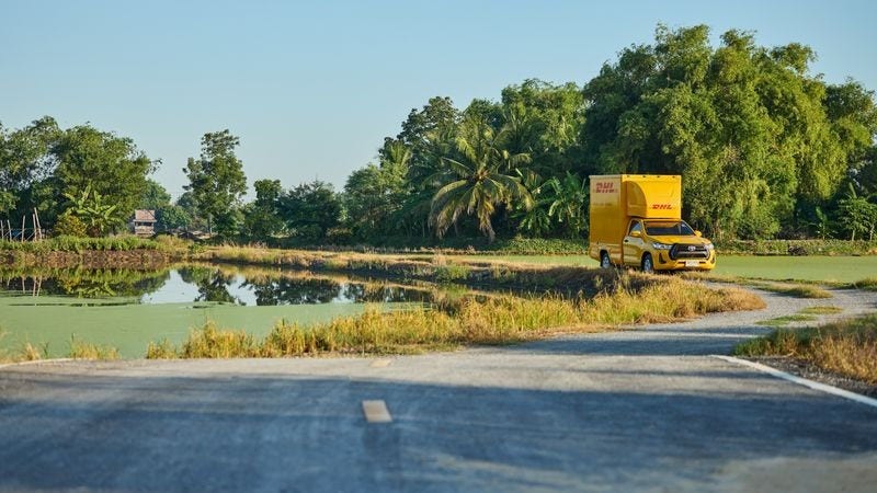 DHL delivery truck driving along a rural road in Thailand, showcasing reliable international shipping services