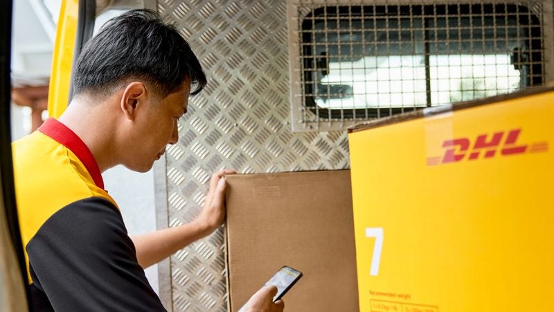 A DHL employee loads a parcel into the back of a van for exporting.