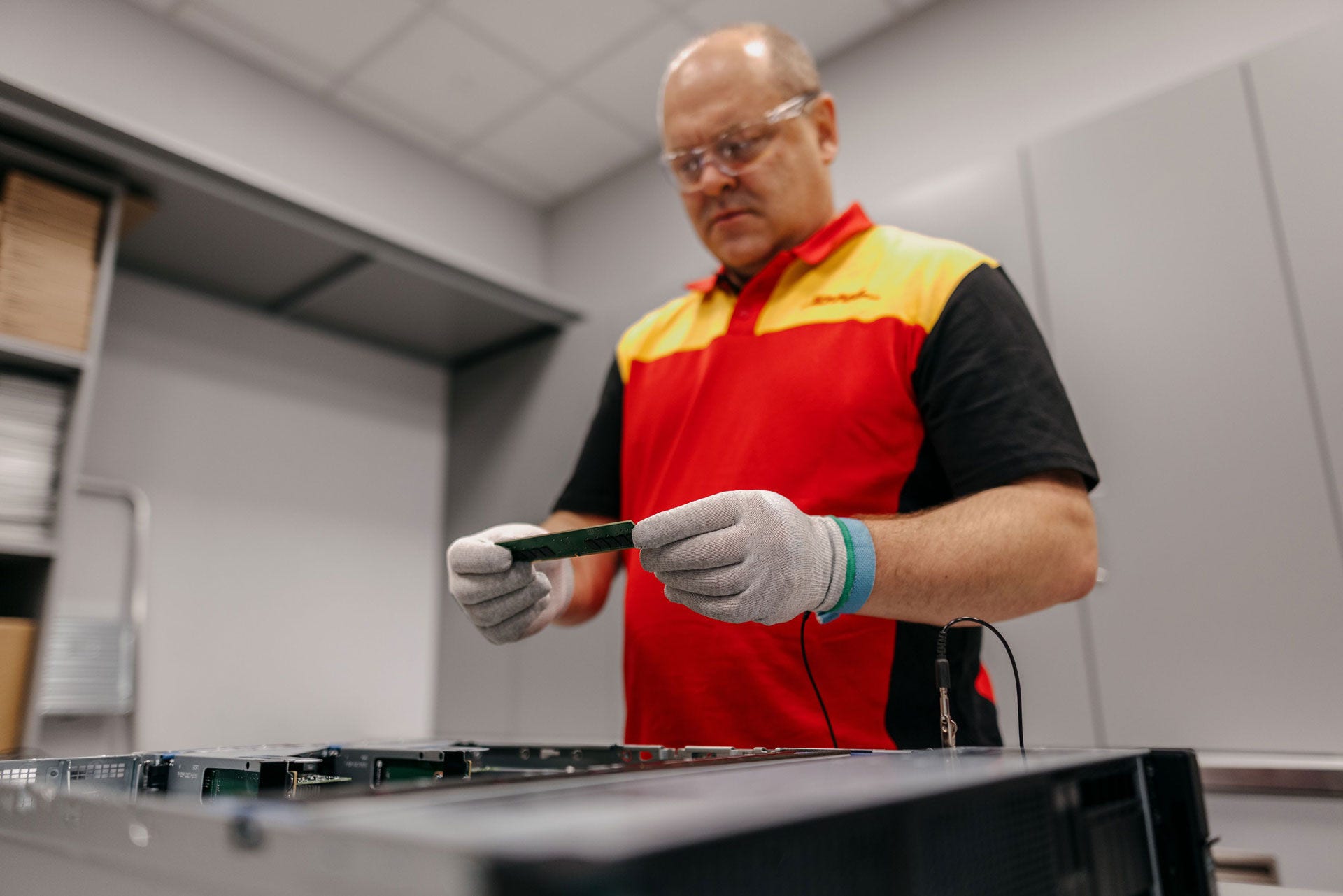 DHL employee wearing static gloves for safety and holding replacement memory card