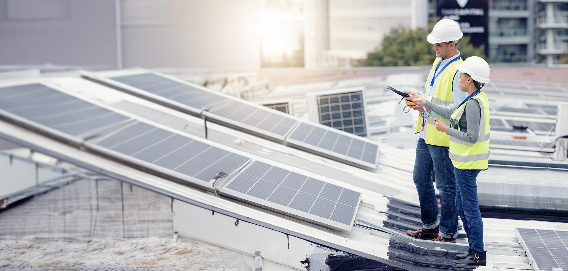 man and woman in hard hats looking at solar panels