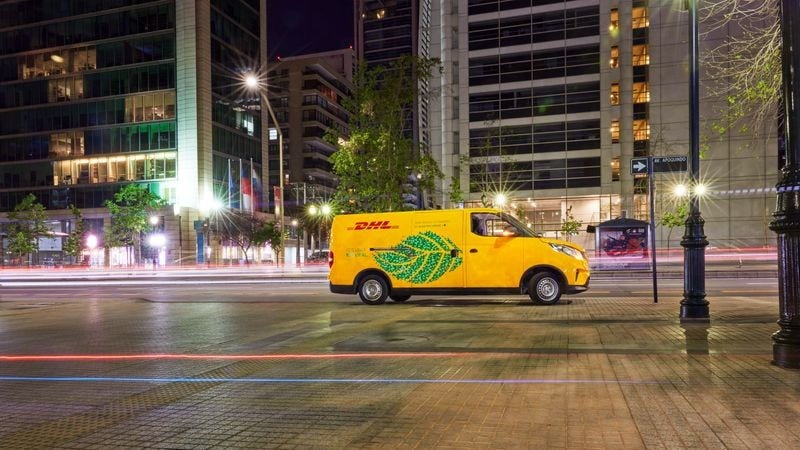 A DHL Express truck driving down a city street at night.