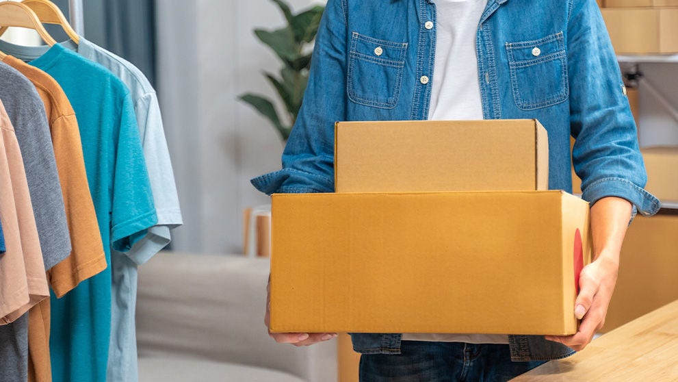 Happy young online seller man holding his packed product boxes to send out to his customer