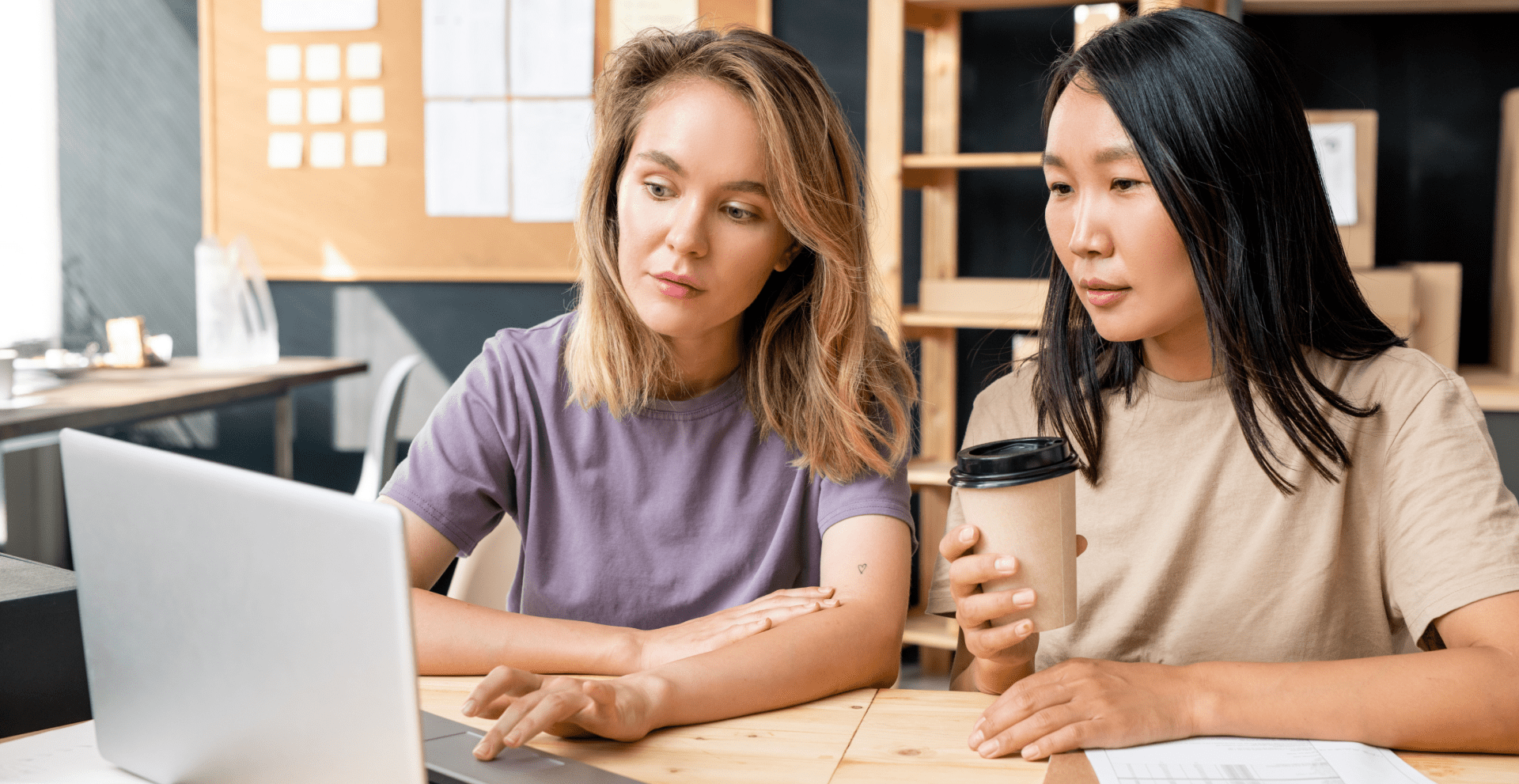 Two women overlook content on a laptop.