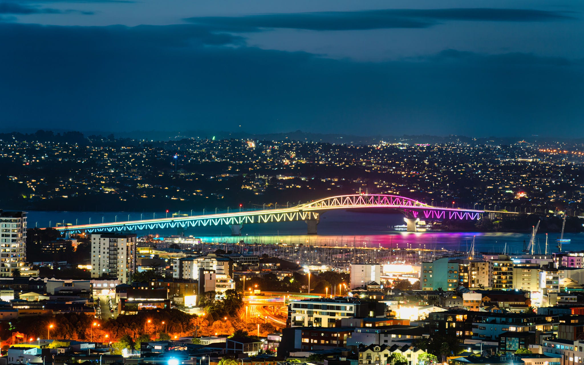 Illuminated rainbow color bridge crossing over the sea by the Auckland harbour at New Zealand