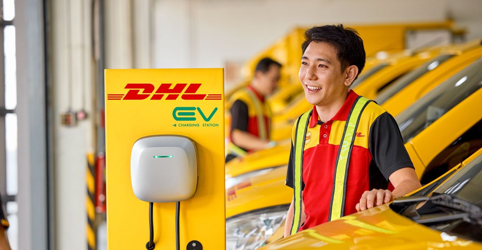 dhl employee standing next to a dhl ev charging station for sustainable logistics