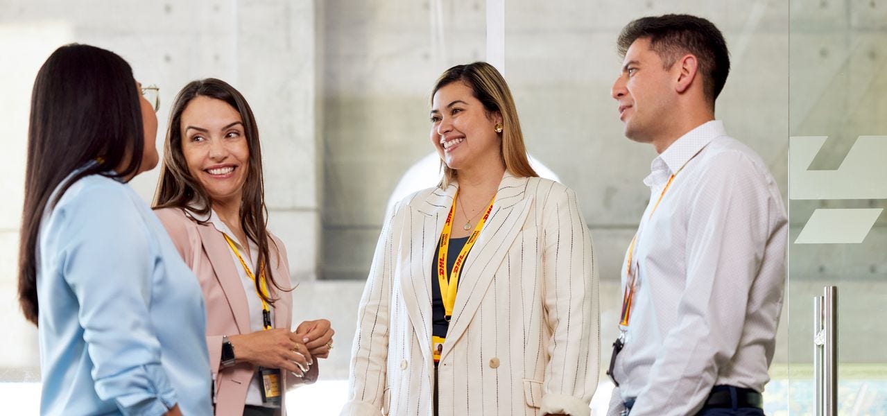 A group of DHL employees is having a conversation in the office