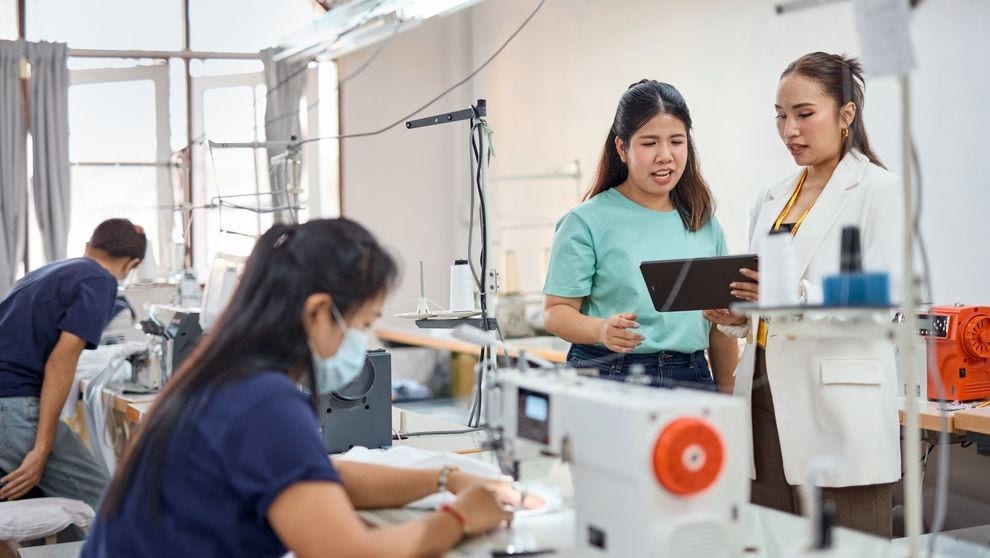 Seamstresses sewing fashion apparel with a DHL expert speaking to the business owner