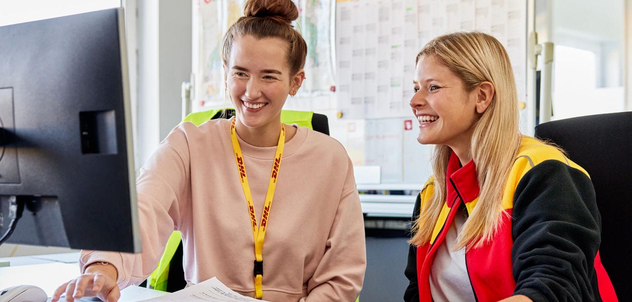 DHL Employees laughing while looking at a computer screen