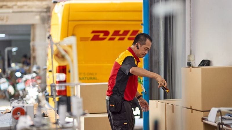 dhl employee scanning shipping labels on parcels and preparing them for transport