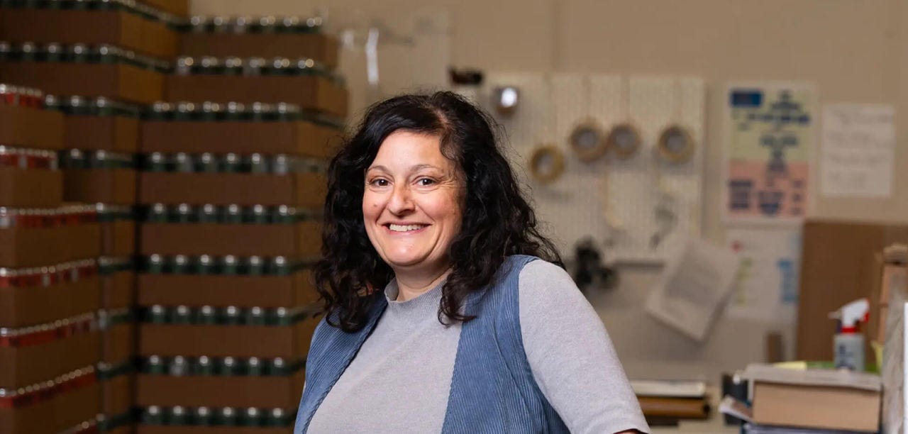 Une femme dans un entrepôt entourée de boîtes de nourriture, organisant des fournitures pour distribution.