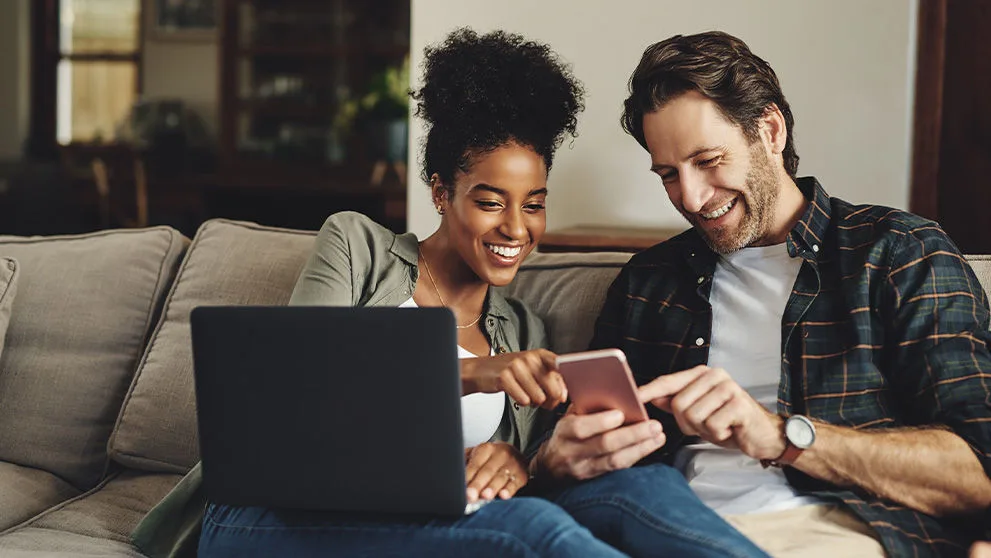Homme et femme souriant devant l’écran du téléphone portable