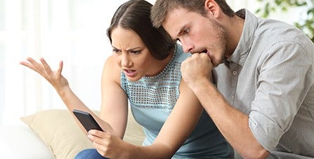 man and woman frowning at mobile phone
