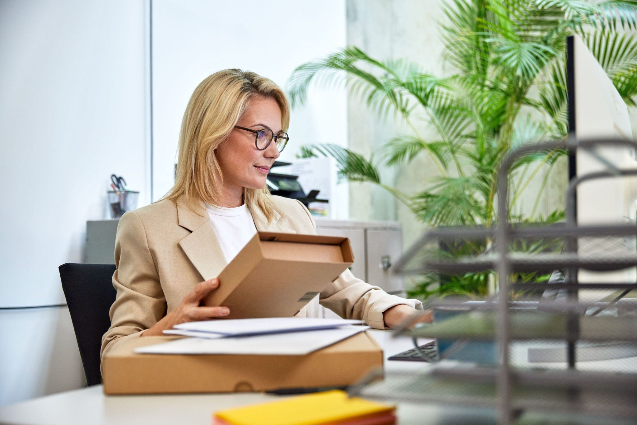 Private Business Kundin hält ein Paket und schaut auf ihren Computer
