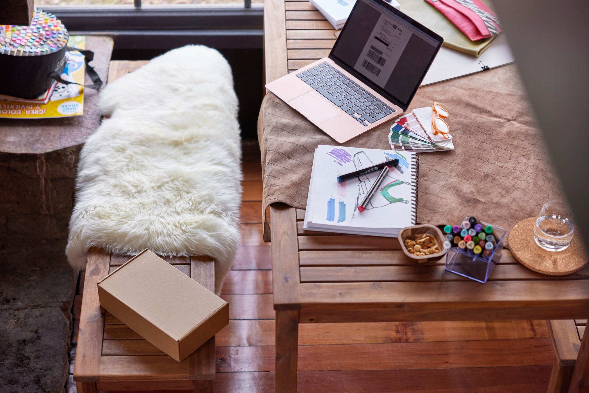 A brown parcel is laying on the bench in a work space located in a rustic cottage. On the laptop Screen on the table, a label, ready to be printed, is visible.