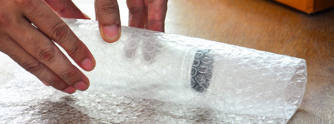 Mand pakker flaske ind i bobleplast