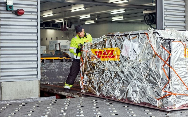 a dhl employee preparing to load a shipment of medical supplies