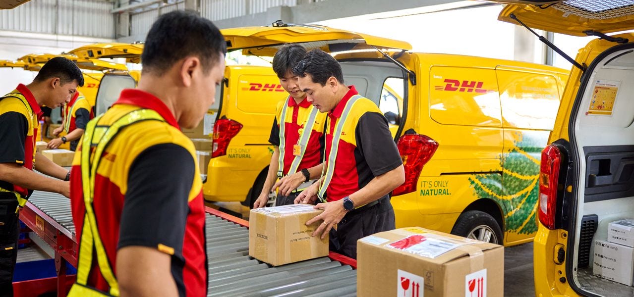 DHL employees sort and load parcels at a service center.