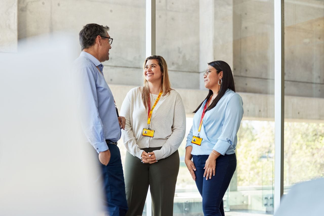 Three DHL employees are having a conversation in the office.