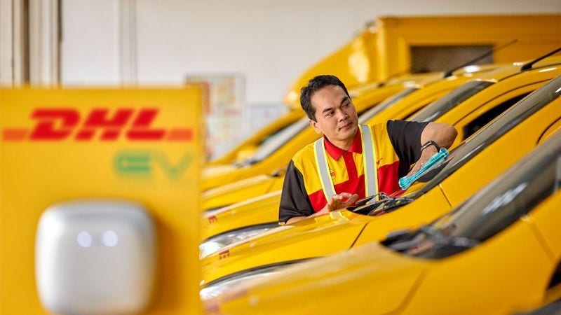 A male DHL employee is cleaning the windshield of an electrical DHL van