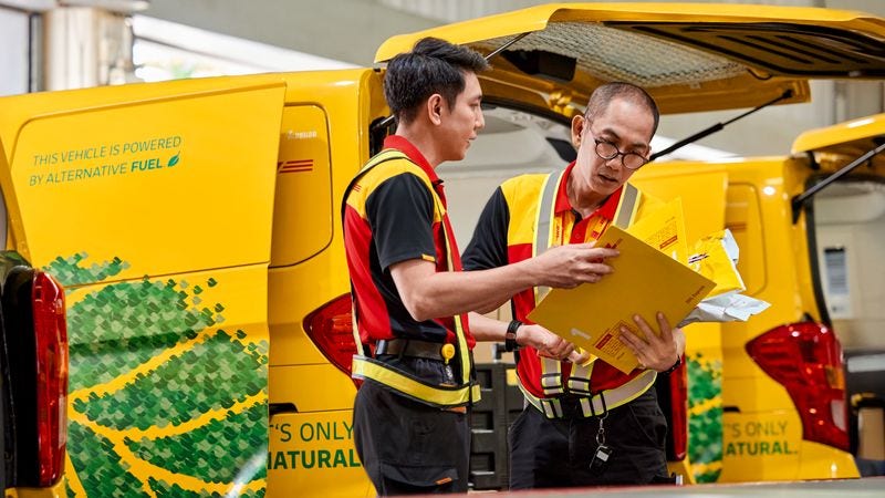 two dhl employees checking the labels of several express envelopes