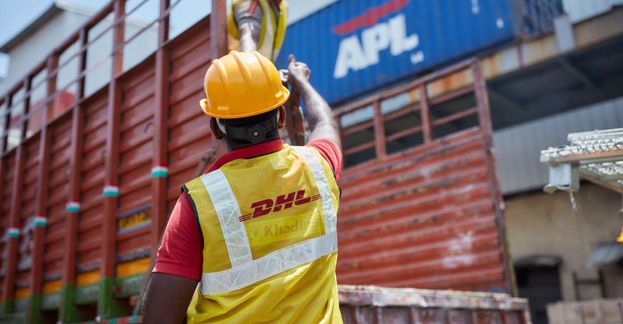 DHL employees load luggage onto a truck as part of their luggage transfer service