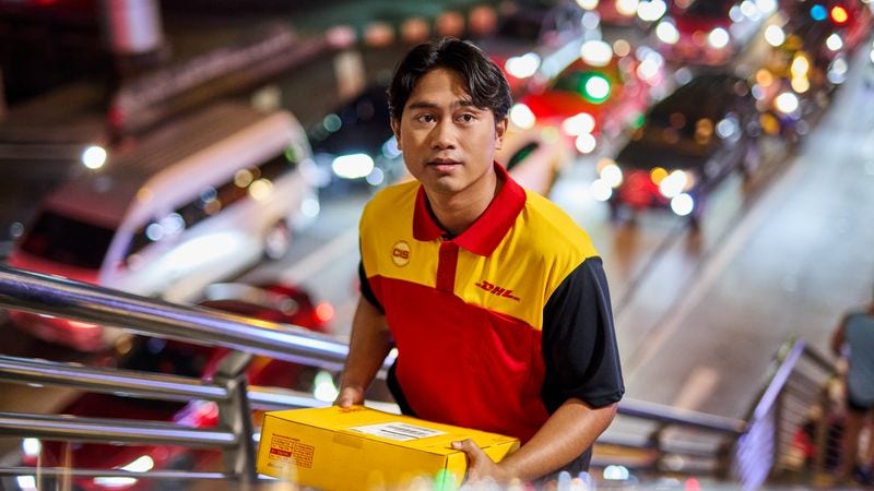 dhl courier delivering a parcel in the city at night