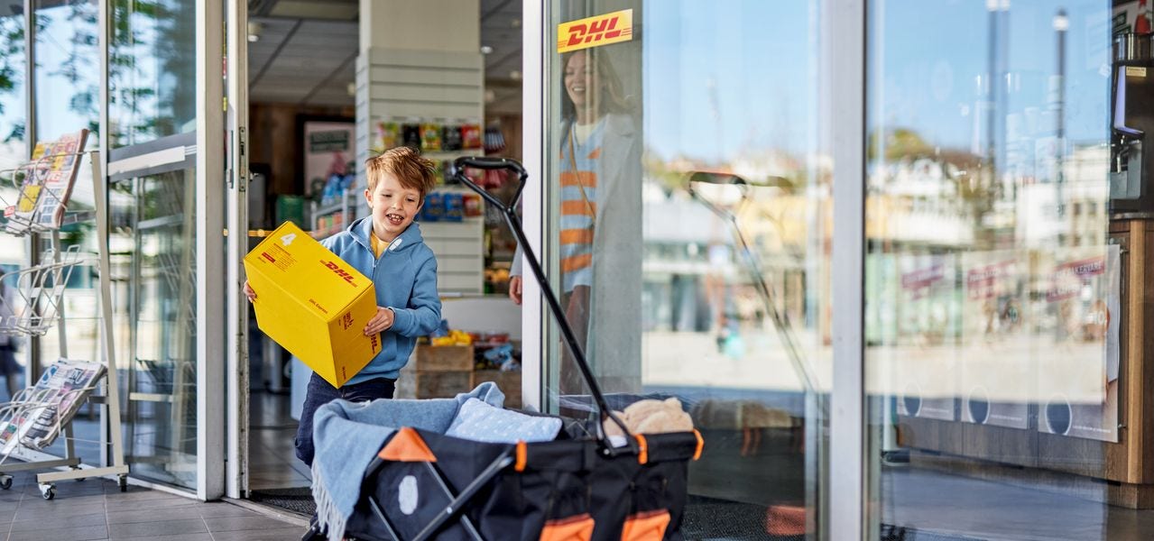 A young boy and his mother are leaving a service point with an express parcel.