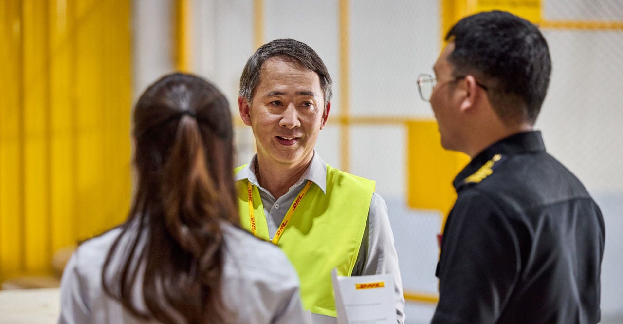 A DHL Express employee talking to customs officers about import tax