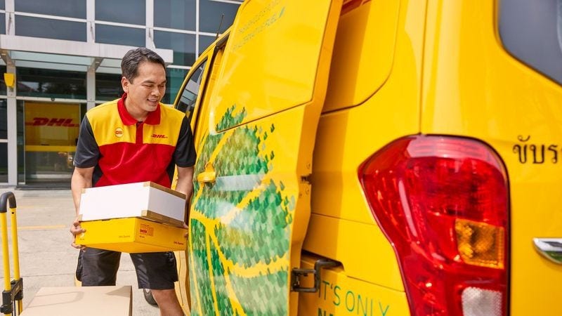 A DHL employee loads parcels into a DHL van.
