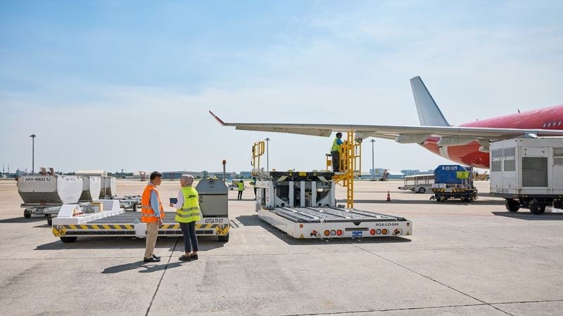 ground staff discuss on the runway with a plane prominently in the background