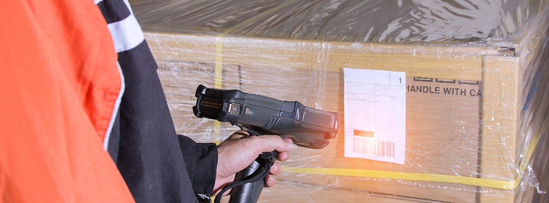 Man worker scanning packages on label with barcode scanner in warehouse