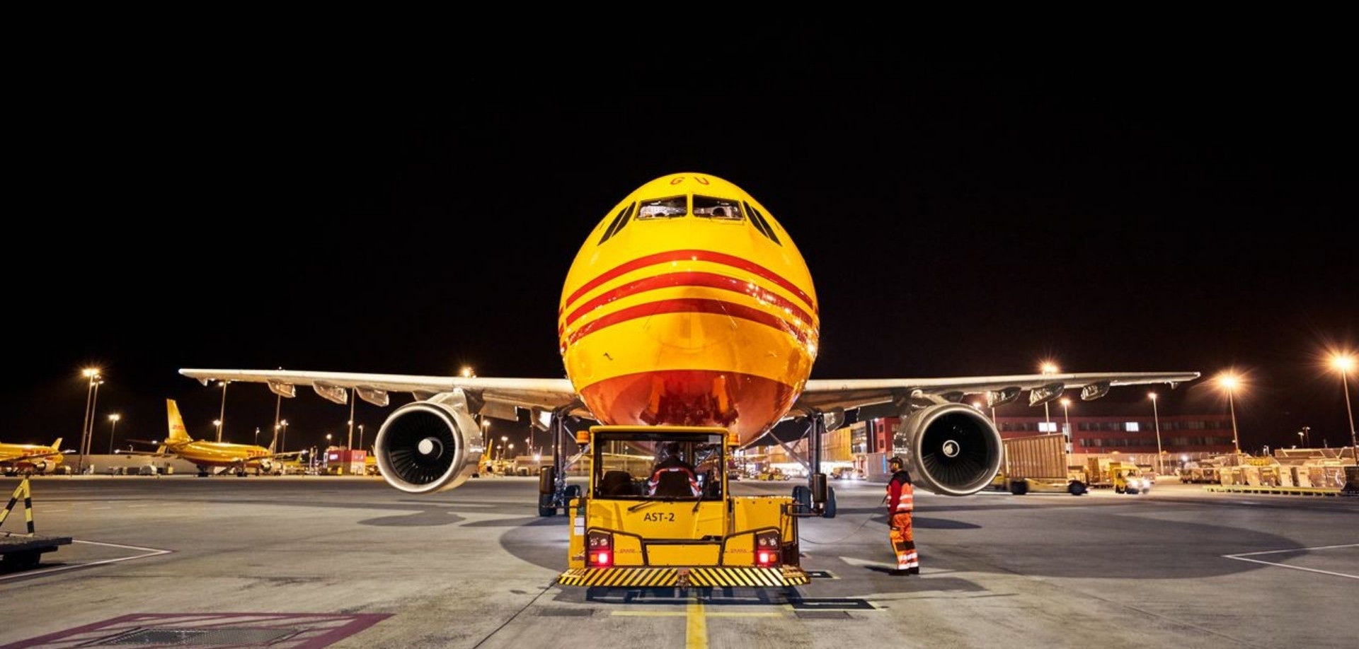 Aeronave cargueira da DHL sendo carregada à noite no pátio do aeroporto