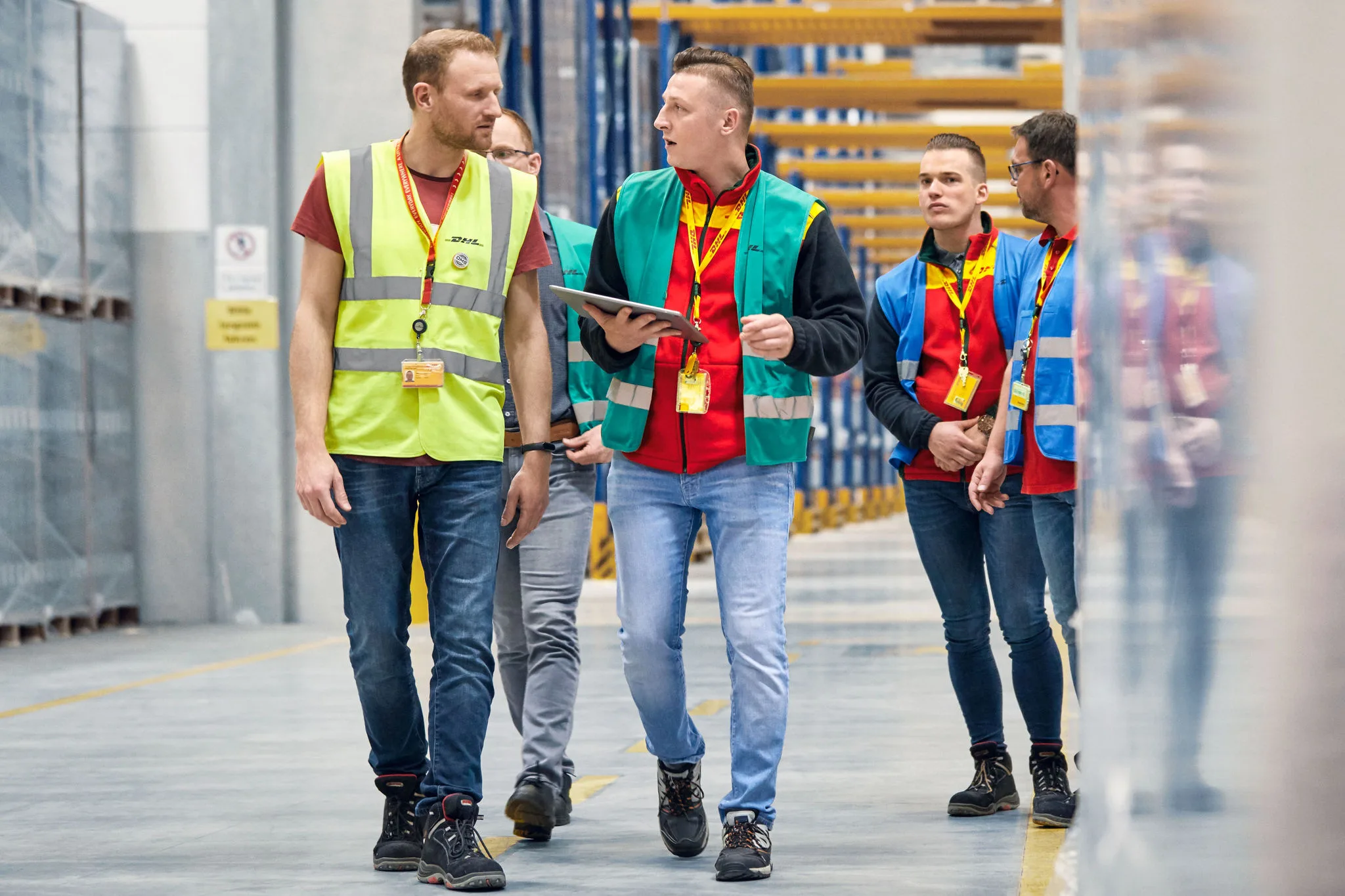 DHL Express employees discussing logistics management in a warehouse