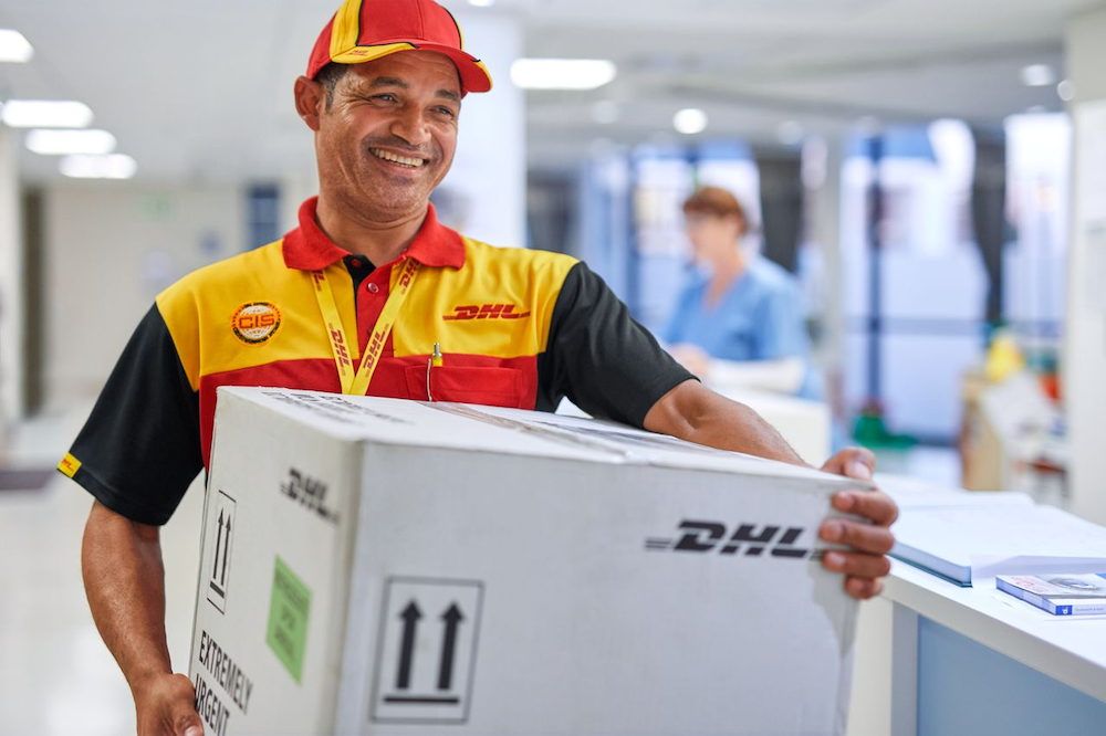 DHL staff walks out of a medical center carrying a parcel