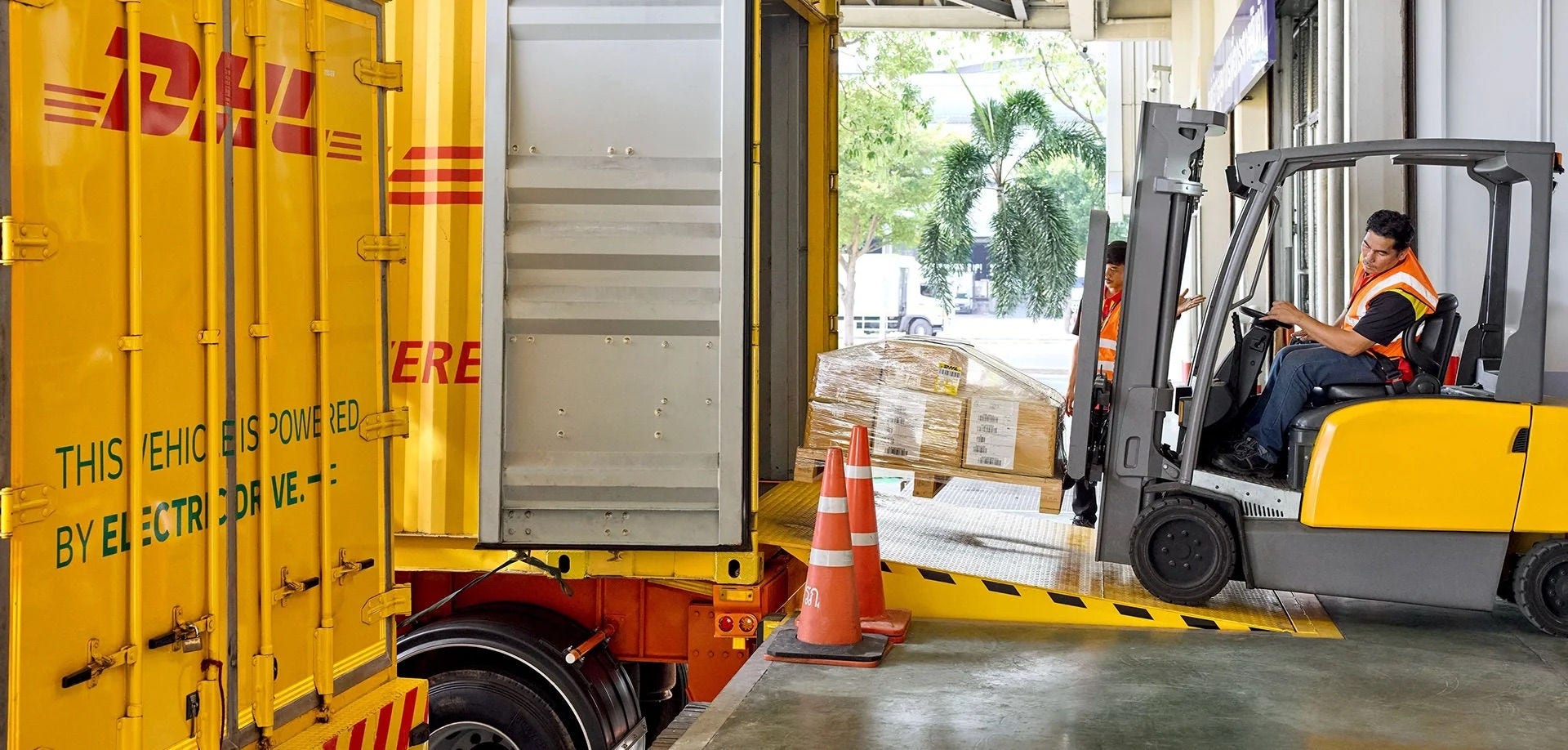 Empilhadeira carregando encomendas paletizadas em um caminhão da DHL