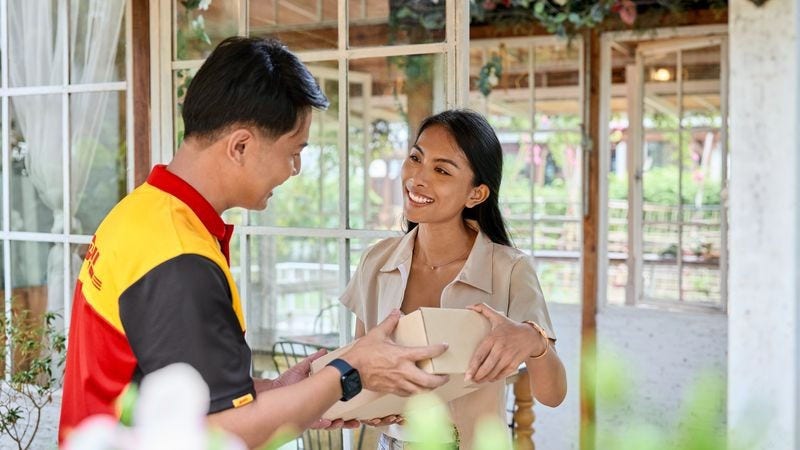dhl express employee receiving a package from a customer to be delivered