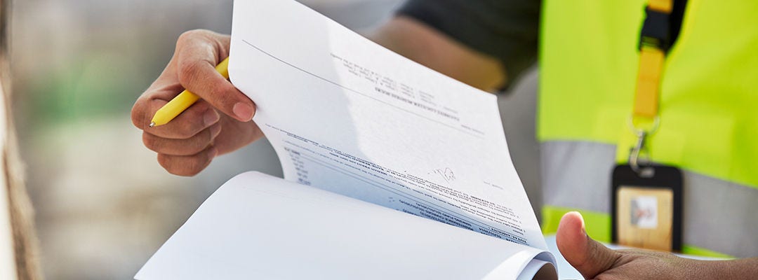 Rukou přehazující papíry a držící žluté pero