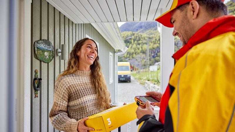 Smiling customer receiving an express parcel delivered by a DHL employee