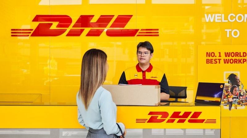 female customer dropping off a brown parcel at a dhl servicepoint