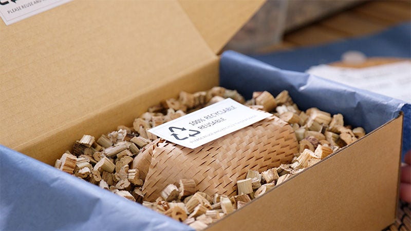 Cardboard box with recycled paper wrap and a plastic free packaging sign