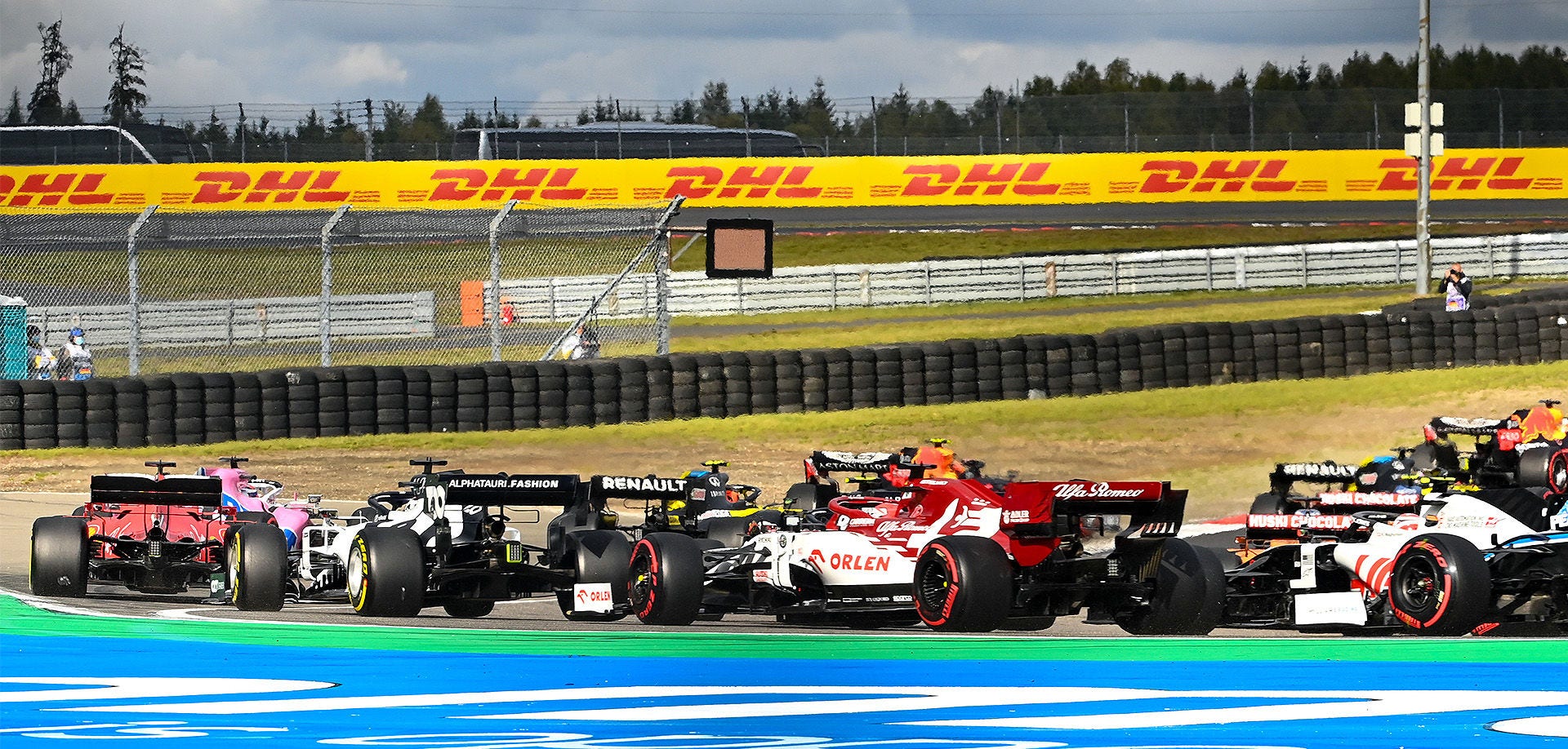 Voitures de course de F1 qui courent avec la bannière DHL englobant la piste.