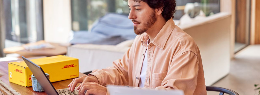 A guy using laptop with DHL Express package on the side