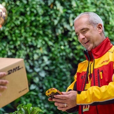 Inline Static (375 x 375 px) - A older male DHL employee prepares his scanner for a signature.