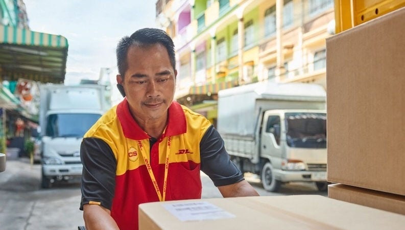 A DHL logistics personnel prepping a package for shipping