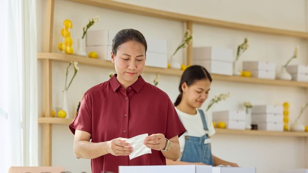 一位女店主正在為一個白色包裹貼標籤，準備出貨。