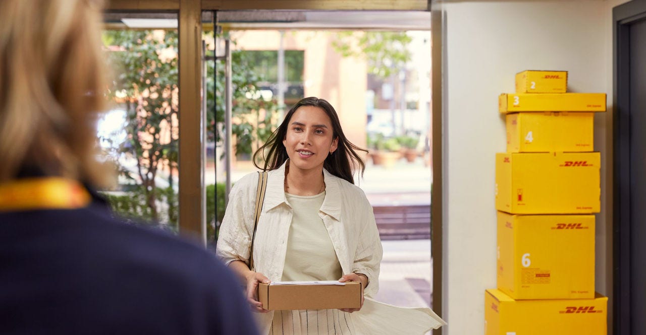 a female customer enters dhl service point with a return parcel
